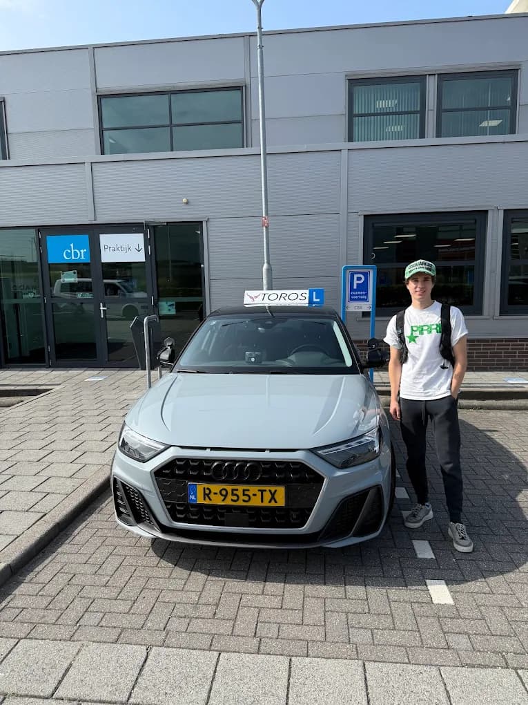 Tevreden leerling naast de lesauto van Rijschool Toros met dakbord TOROS bij het CBR.